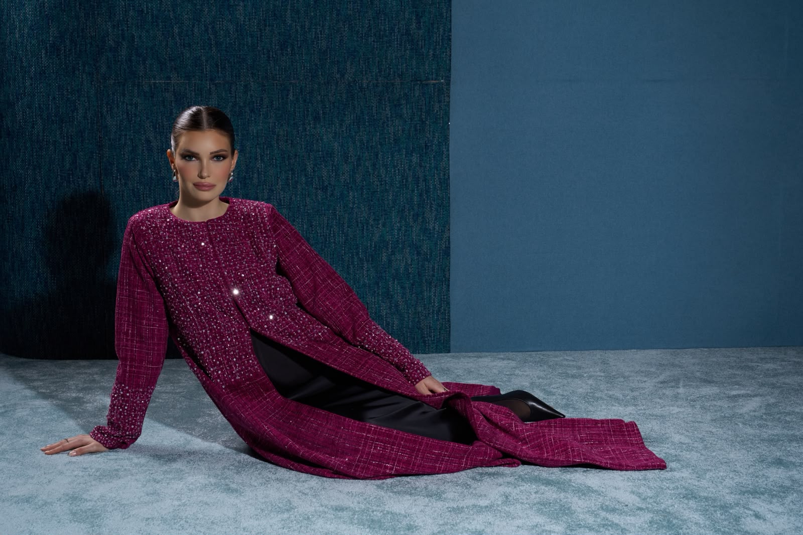 Hissa Line burgundy abaya against a textured blue backdrop